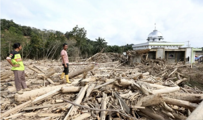 Relawan bencana melihat tumpukan gelondongan kayu di belakang masjid Nurussalam, Desa Lubuk Sidup, Aceh Tamiang, Aceh, Minggu (28/12/2025). Bencana banjir bandang akibat luapan sungai Tamiang pada 26 November 2025 mengakibatkan 200 unit lebih rumah warga rusak berat dan hanya menyisakan bangunan masjid Nurussalam di Desa Lubuk Sidup. ANTARA FOTO/Irwansyah Putra/foc. (ANTARA FOTO/IRWANSYAH PUTRA)